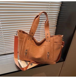 Detail shot of the large brick orange tote bag showing wide strap and metallic ring