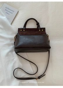 Detail of dark brown suede Kelly bag with gold metal hardware and adjustable strap