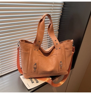 Detail of a vintage canvas tote bag with adjustable wide strap and metallic stud accents