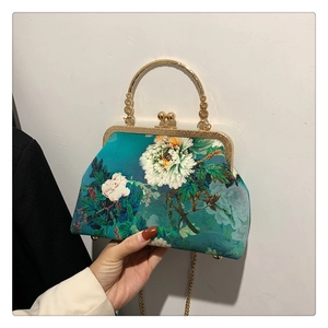 Detailed view of peacock blue floral handbag with metal handle and retro frame