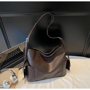 Detail of dark coffee PU leather tote with adjustable strap and practical side pockets