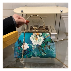 Macro view of blue floral frame bag featuring golden metal handle and beaded clasp