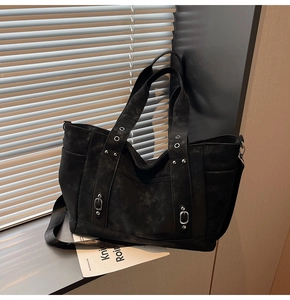 Detail view of black vintage tote bag with silver metal eyelets, rivets and adjustable strap