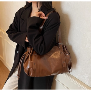 Détail d'un sac cabas marron foncé en similicuir avec finition cirée et boucle en métal