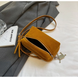 Detail of ginger yellow matte suede box bag featuring silver robot charm and metal zipper