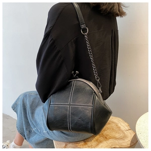 Detail of vintage black shell bag with metal kiss lock and white cross stitching
