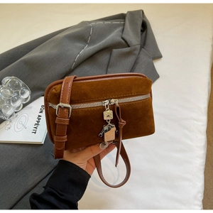 Detail of vintage brown suede crossbody bag with a creative silver robot zipper charm