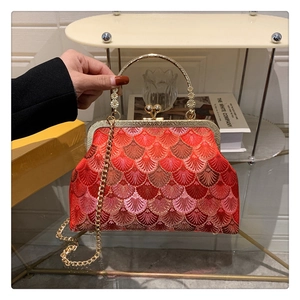 Detailed embroidery texture on red fish scale evening bag with golden floral metal frame