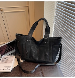 Detail view of large black tote bag with vintage texture and metallic rivets