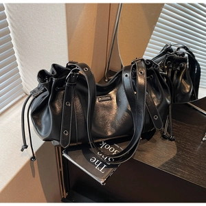 Détail du sac hobo en cuir noir avec fermeture à cordon et œillets métalliques argentés