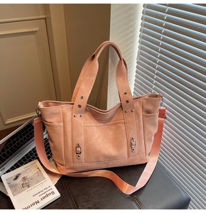 Detail of nude pink tote bag with metal studs and wide nylon shoulder strap on desk