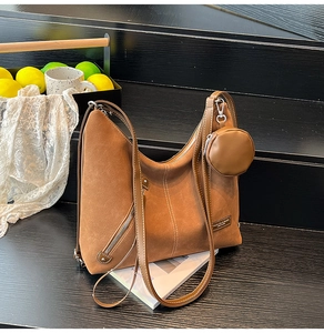 Detail of brown suede tote bag with contrast stitching and small round coin purse charm