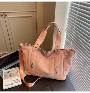Detail view of pink vintage tote bag showing matte texture and rivets on an office desk