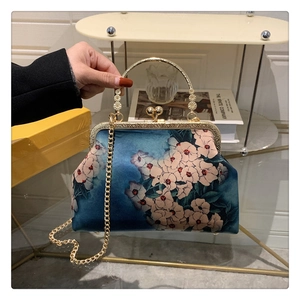 Detailed view of elegant vintage floral print handbag with golden metal kiss-lock handle