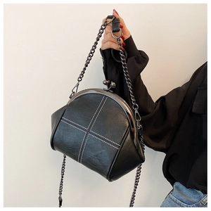 Macro shot of black PU leather shell bag showing white cross stitching and dark grey clasp