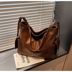 Detailed macro view of caramel brown PU leather texture and side pocket design on tote bag