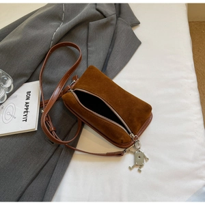 Detail of vintage brown suede crossbody bag with a unique silver robot zipper pendant