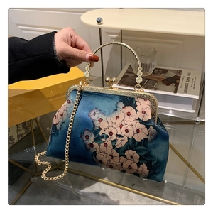 Detail of vintage navy floral handbag with engraved gold handle and metal chain strap