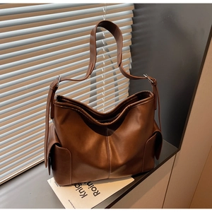 Detail view of large brown PU leather tote bag with side pockets on a window sill
