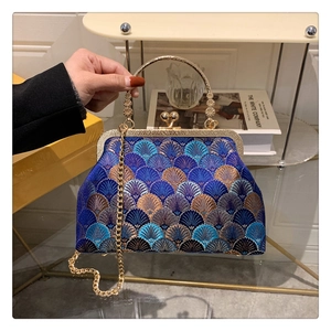 Detailed macro view of the intricate blue embroidery and gold clasp on the vintage handbag