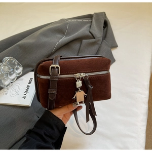 Detail of dark brown suede crossbody bag with silver zipper and robot charm accessory