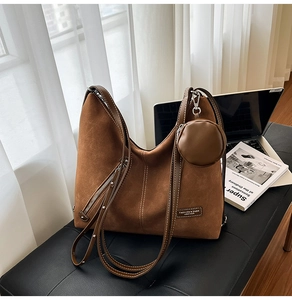 Close-up of vintage brown suede tote bag with round coin purse and white stitching