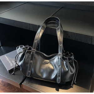 Détail du sac bandoulière en cuir PU brillant noir avec cordons et plaque logo métal
