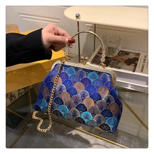 Close-up of vintage fan-shaped blue embroidery on a classic frame handbag with gold handle