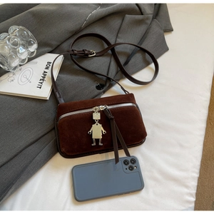 Détail du sac bandoulière en daim marron avec pendentif robot et smartphone pour échelle