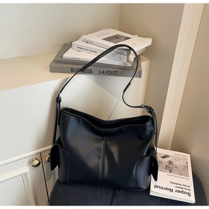 Detail of black PU leather tote bag with functional side pockets and adjustable strap