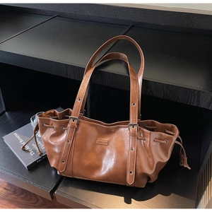 Détail d'un sac cabas en similicuir marron avec cordon de serrage sur support en bois