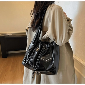 Detail of black motorcycle style tote bag with silver studs and long leather tassels