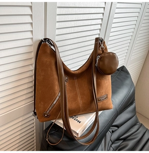 Brown suede tote bag with leather strap and coin purse against white shutters