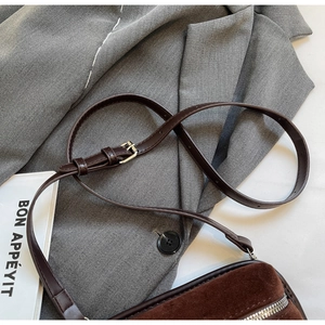 Detailed macro shot of brown suede crossbody bag with silver zipper and leather strap