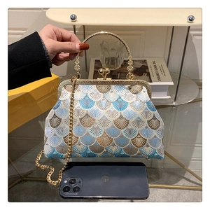 Detail of vintage embroidered shell pattern handbag with metal clasp and chain strap