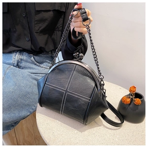 Detail of black lychee grain shell bag featuring white cross-stitch and metal chain strap
