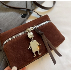 Close-up of vintage brown suede bag with silver robot charm and metal zipper detail