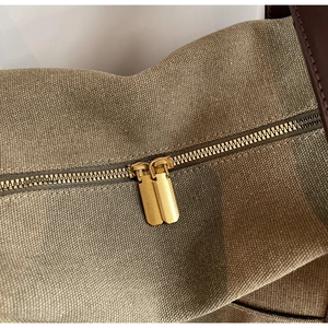 Macro detail of high-quality canvas fabric with dual golden zippers and leather edge trim