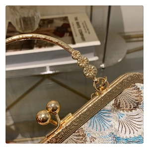 Macro view of blue embroidery pattern with gold metal frame and handle for vintage bag