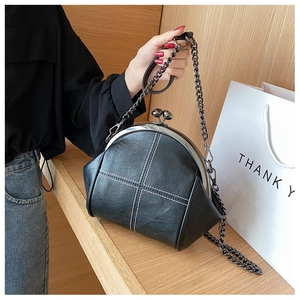 Detail of vintage black shell bag with white cross stitching and metal chain strap