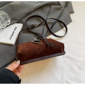 Détail de la petite sacoche en daim marron foncé avec pendentif argenté et sangle