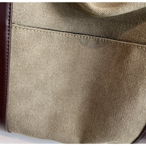 Macro shot of khaki canvas and brown leather stitching details on a large tote bag