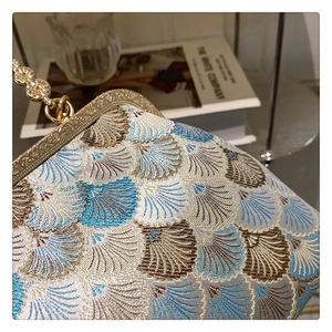 Macro detail of French vintage clutch bag with blue scallop pattern and gold metal frame