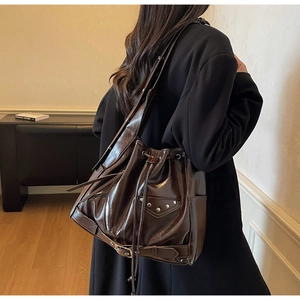 Detail of vintage dark brown bucket bag with silver studs and polished oil wax leather texture