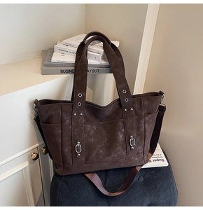 Detail of vintage brown suede tote bag featuring side pockets and metal rivets decorations