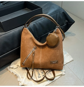 Detail of caramel hobo bag featuring contrast stitching, side zipper, and coin purse