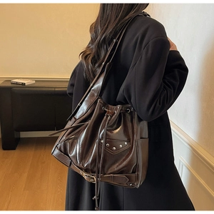 Detail view of dark brown oil wax leather bucket bag with silver studs and zipper accents