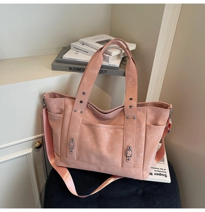 Detail of dusty pink canvas tote bag showing wide handle straps and side pockets