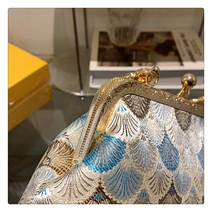 Detailed macro shot of vintage gold metal frame and ornate brocade fabric on handbag
