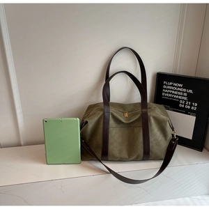 Detail of olive green canvas tote with brown leather handles and adjustable shoulder strap